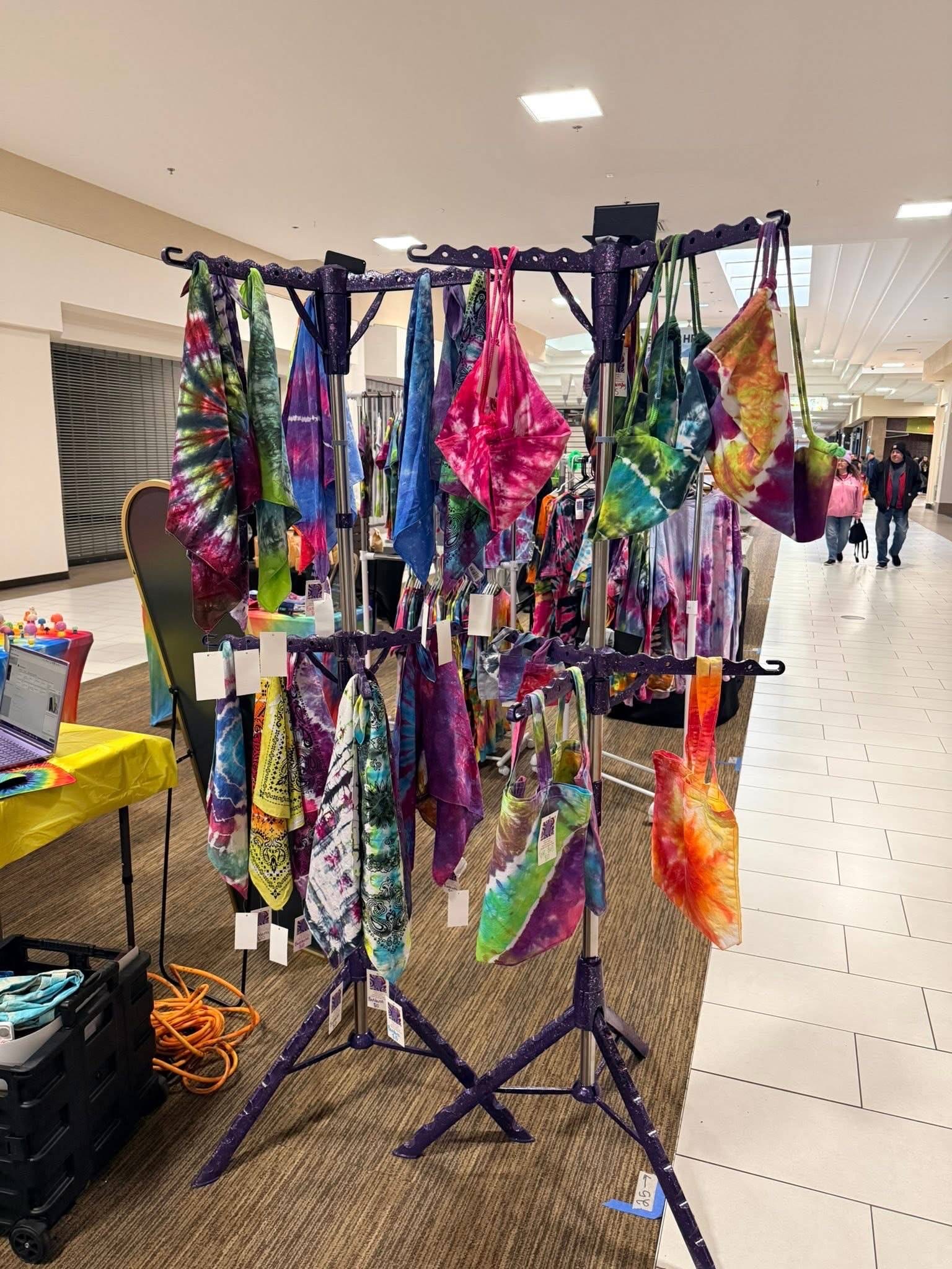AlliPop tie-dye hanging on racks at a market
