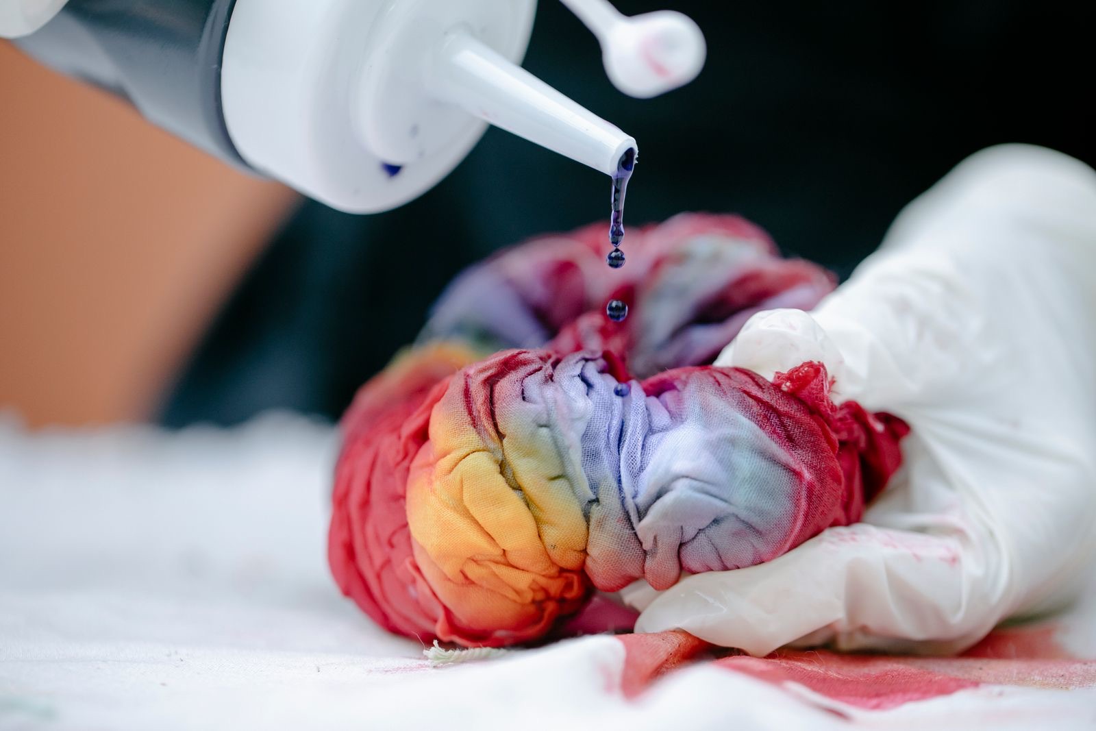 Dye dripping from a squeeze bottle onto a tied rainbow bundle