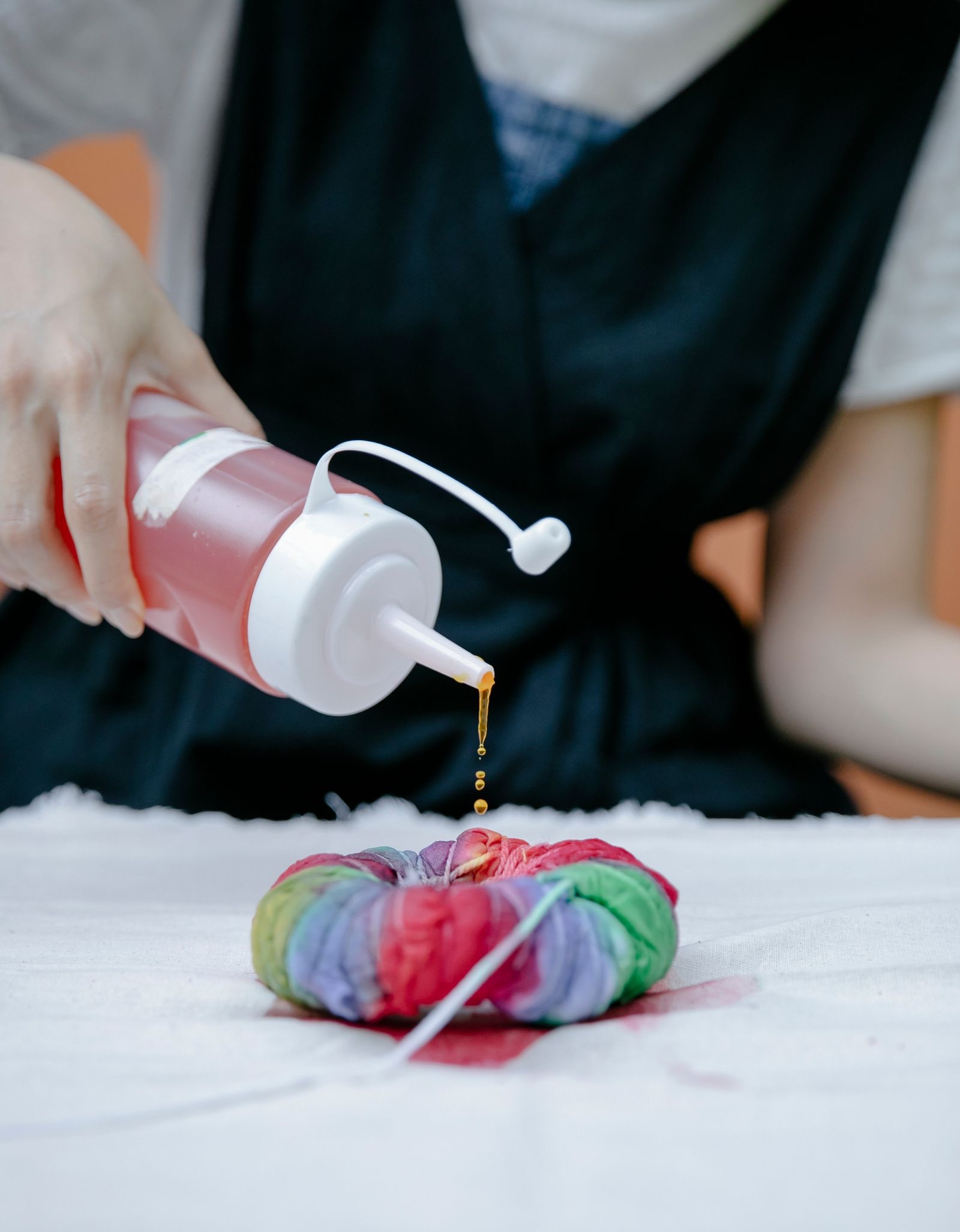 Dye being poured from a squeeze bottle onto a tied shirt